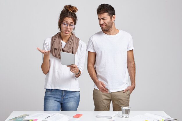 Junge Frau und Ehemann stehen zusammen am Schreibtisch