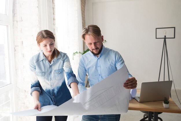 Junge Frau und Mann, die an Plan im Büro arbeitet