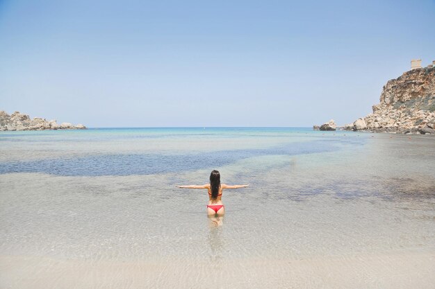 junge Frau von hinten im Wasser am Meer