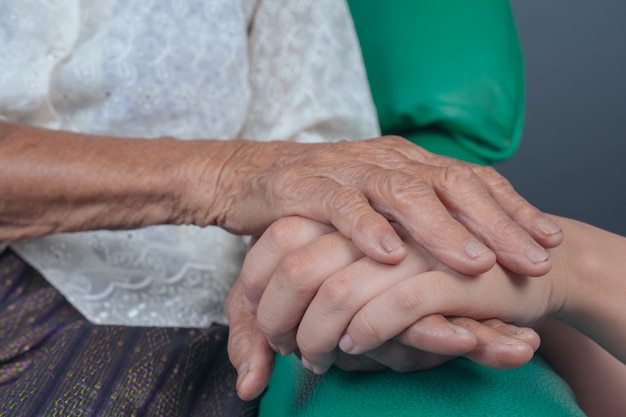 Junge Frau, welche die Hand einer älteren Frau hält.