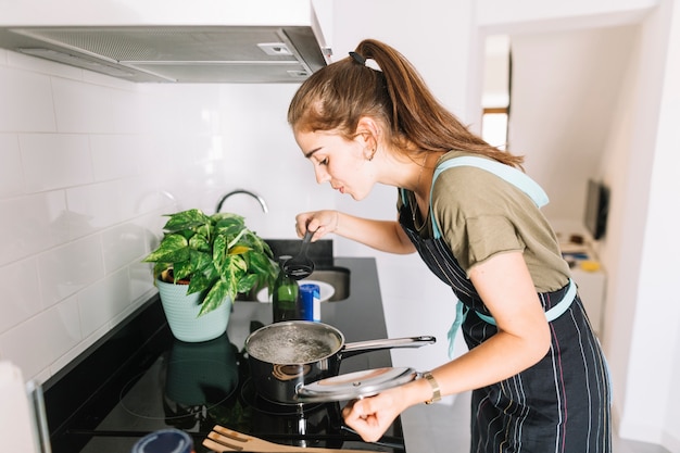 Junge Frau, welche die Suppe in der Küche schmeckt