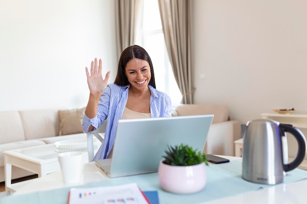 Junge Frau winkt auf Laptop und spricht mit ihren Freunden per Videoanruf Studentin spricht per Videokonferenzanruf Lehrerin Trainerin Nachhilfe per Webcam Online-Schulung Ecoaching-Konzept