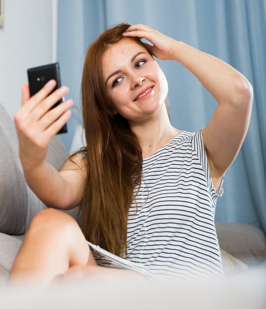 Junge Frau wirft für selfie auf dem Sofa auf