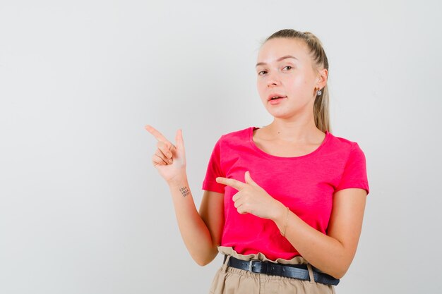 Junge Frau zeigt auf die obere linke Ecke im T-Shirt und in der Hose