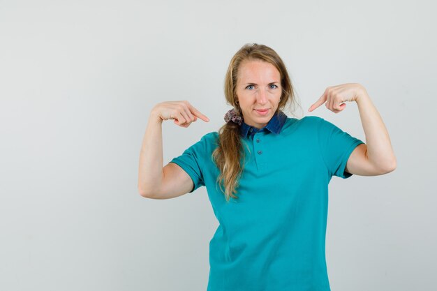 Junge Frau zeigt auf sich im T-Shirt und schaut stolz