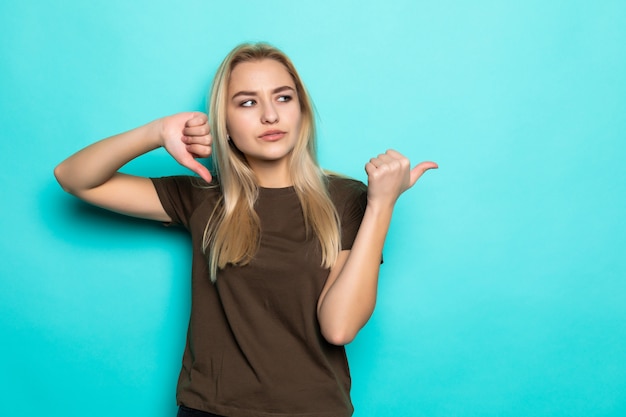 Kostenloses Foto junge frau zeigte seite auf blaue wand