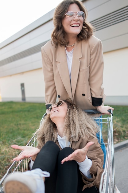 Junge Frauen der Vorderansicht, die mit Einkaufswagen spielen