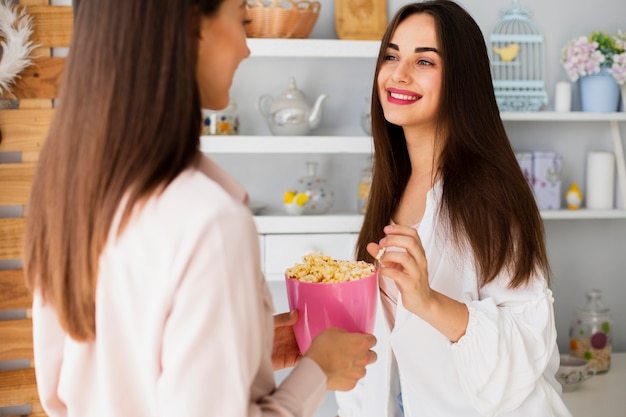 Junge Frauen der Vorderansicht, die Popcorn teilen