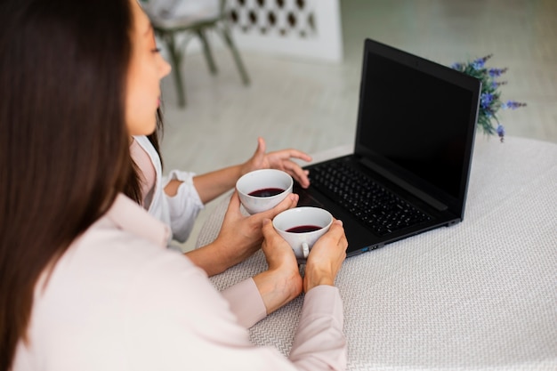 Junge Frauen des hohen Winkels zu Hause, die Laptop betrachten