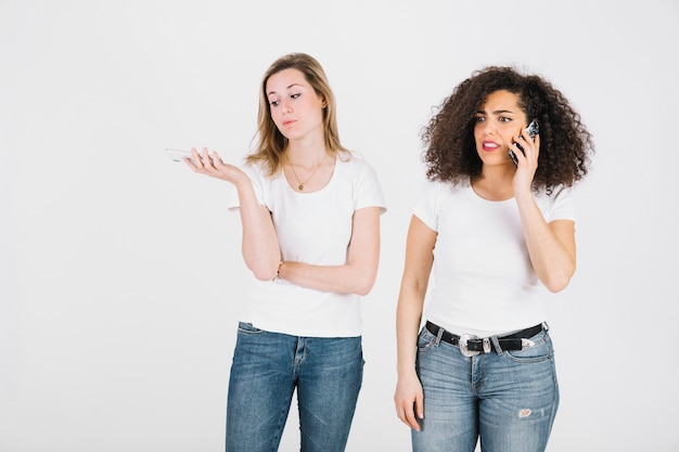 Junge Frauen, die an Telefonen sprechen