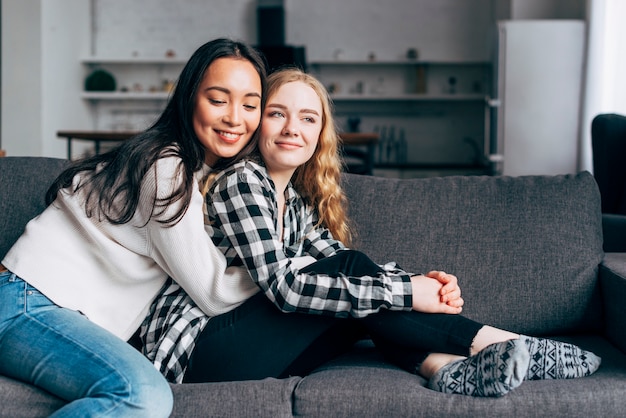 Kostenloses Foto junge frauen, die auf sofa umfassen