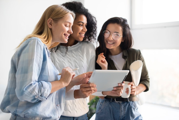 Junge Frauen, die auf Tablette schauen