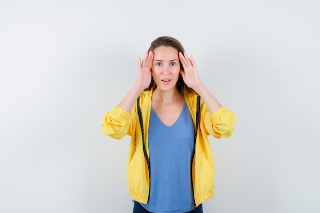 Junge Frauen, die Händchen halten, um in T-Shirt, Jacke und erstauntem Aussehen deutlich zu sehen. Vorderansicht.