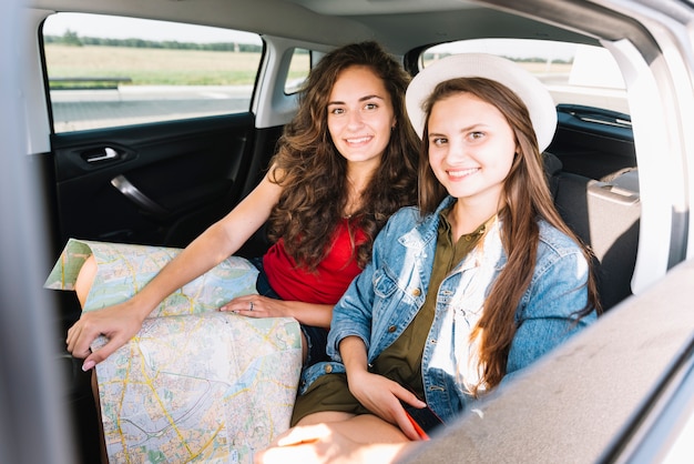 Junge Frauen, die mit Karte im Autoinnenraum sitzen