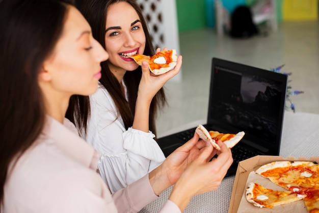 Junge Frauen, die Pizzamahlzeit genießen