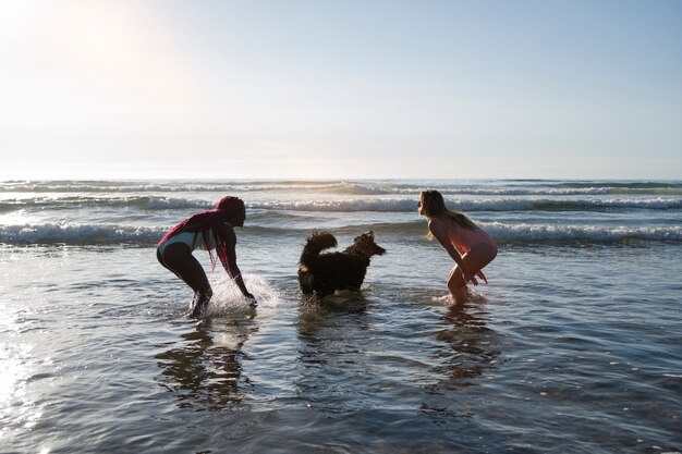 Junge Frauen haben Spaß mit Hund am Strand