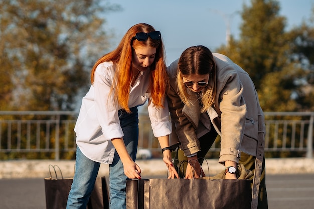 Junge Frauen mit Einkaufstüten auf dem Parkplatz