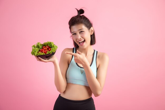 Junge Frauen mögen Gemüse auf einem Rosa essen.