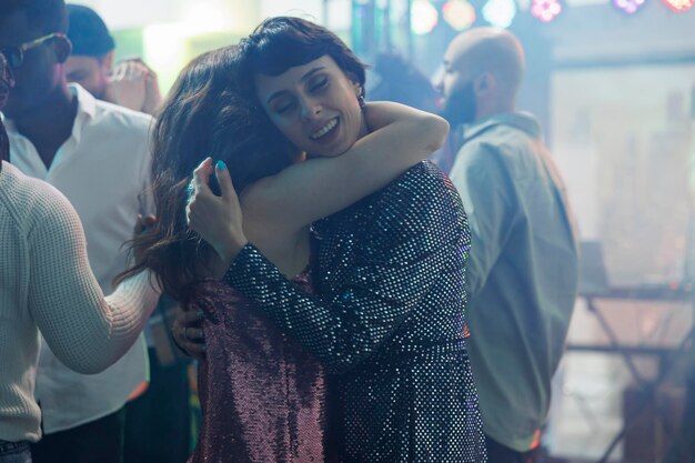 Junge Frauen umarmen und tanzen, während sie eine Disco-Party im Nachtclub besuchen. Romantisches Freundinnenpaar umarmt sich auf der Tanzfläche beim Clubbing und Entspannen bei einer Diskothekenveranstaltung im Club