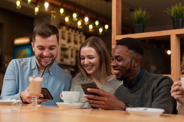 Junge Freunde, die Telefone am Restaurant verwenden