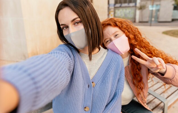 Junge Freundinnen mit Gesichtsmasken im Freien nehmen ein Selfie