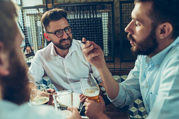 Junge fröhliche Menschen lächeln und gestikulieren, während sie sich in der Kneipe entspannen