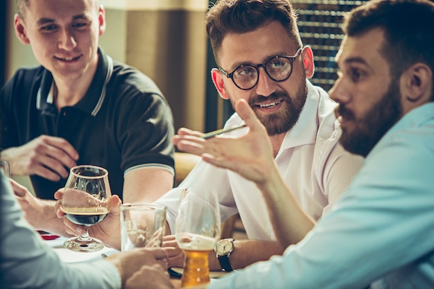 Kostenloses Foto junge fröhliche menschen lächeln und gestikulieren, während sie sich in der kneipe entspannen.