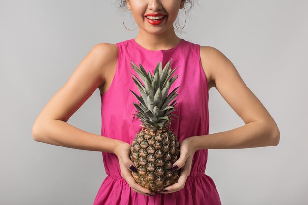 Junge gebräunte Frau im rosa Hemd, das Ananas, positive Emotion, isoliert, tropische Frucht, Diät, lächelnd, rote Lippen hält