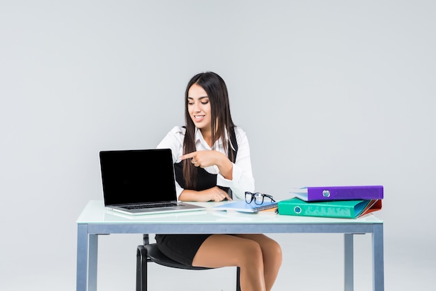 Junge Geschäftsfrau auf einem Laptop am Schreibtisch lokalisiert auf Weiß