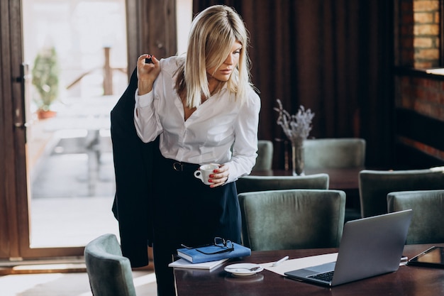 Kostenloses Foto junge geschäftsfrau, die am computer in einem café arbeitet