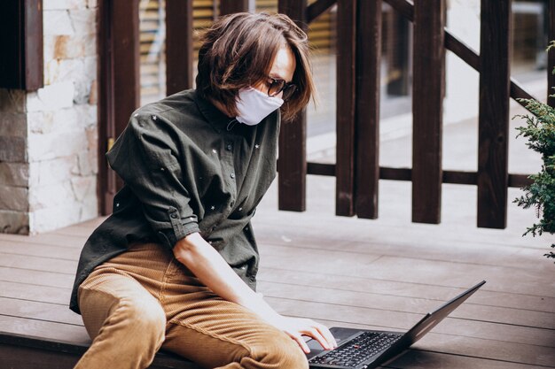 Junge Geschäftsfrau, die am Computer von zu Hause in der Maske arbeitet