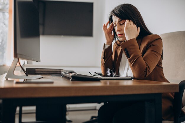 Junge Geschäftsfrau, die am Schreibtisch sitzt und am Computer arbeitet