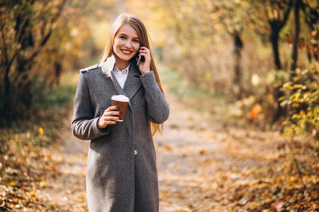 Junge Geschäftsfrau, die am Telefon spricht und Kaffee trinkt