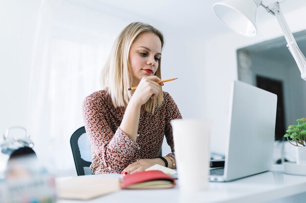 Junge Geschäftsfrau, die an Laptop im Büro arbeitet