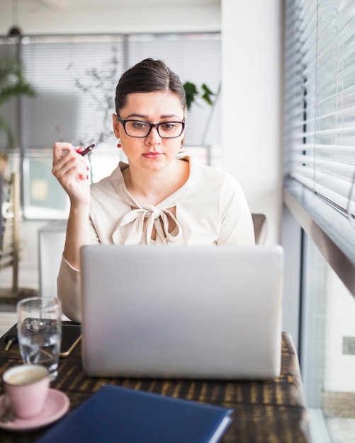 Kostenloses Foto junge geschäftsfrau, die an laptop in der kaffeestube arbeitet