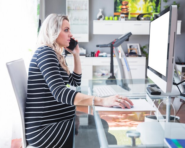 Junge Geschäftsfrau, die auf Mobiltelefon im Büro spricht