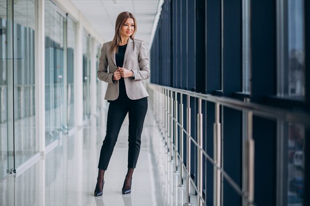 Junge Geschäftsfrau, die durch das Fenster in einem Büro steht