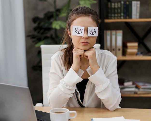 Junge Geschäftsfrau, die ihre Augen mit gezeichneten Augen auf Papier bedeckt