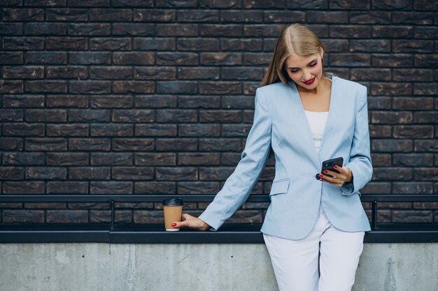 Junge Geschäftsfrau, die Kaffee trinkt und am Telefon spricht