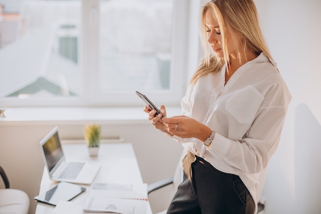 Junge Geschäftsfrau, die Telefon im Büro benutzt