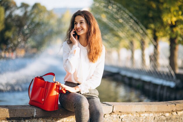 Junge Geschäftsfrau, die Telefon im Park zur Mittagspause verwendet