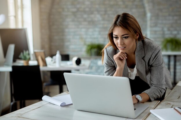 Junge Geschäftsfrau, die während der Arbeit im Büro auf einem Computer im Internet surft