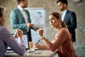 Kostenloses Foto junge geschäftsfrau, die während des meetings im büro mit ihrer kollegin spricht