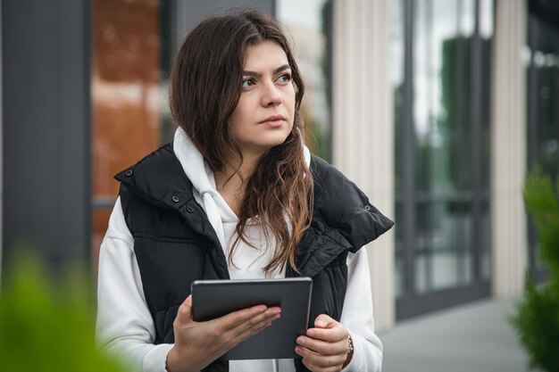 Junge Geschäftsfrau mit einem Tablet auf dem Hintergrund des Gebäudes