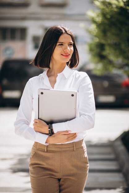 Junge Geschäftsfrau mit Laptop außerhalb der Straße