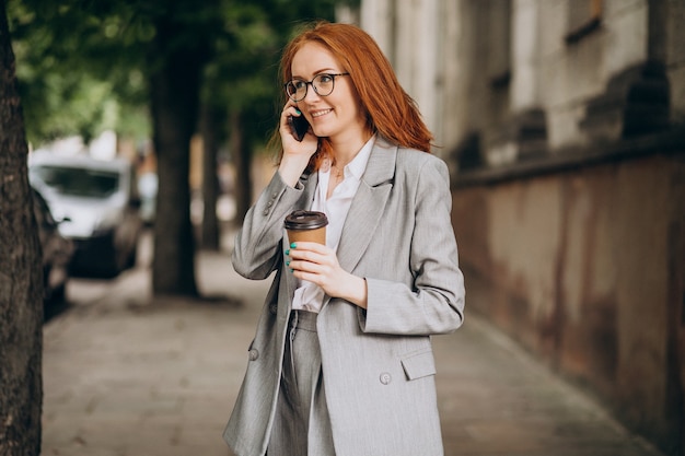 Junge Geschäftsfrau mit roten Haaren mit Telefon