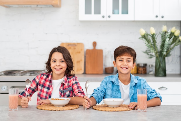 Junge Geschwister der Vorderansicht, die zusammen Frühstück essen