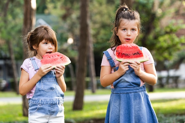 Junge Geschwister, die Wassermelone draußen essen