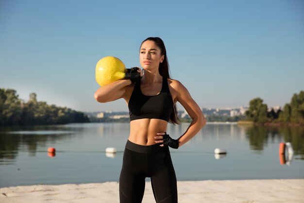 Junge gesunde Sportlerin, die Training am Strand macht