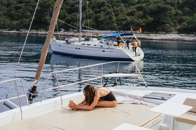 Junge gesunde und ruhige Frau, die Yoga auf Segeljachtboot im Meer in Insel tut